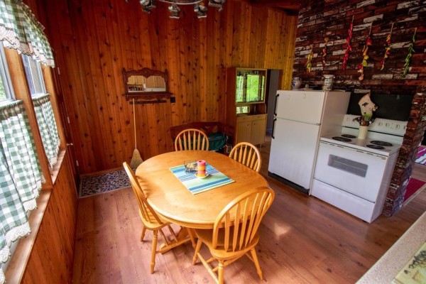 Dining area with a wooden table, chairs, and a brick accent wall with a white refrigerator. - 257 Ta-wa-pit Drive, Clear Lake