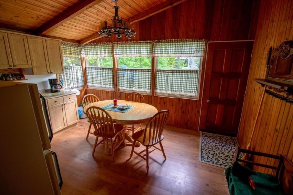 Dining area with a wooden table, chairs, and windows with checkered curtains. - 257 Ta-wa-pit Drive, Clear Lake