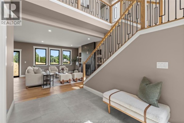 Living room and entryway of a home with a staircase, light wood floors, and neutral furniture. - 2572 Mayfair Avenue South, Lasalle