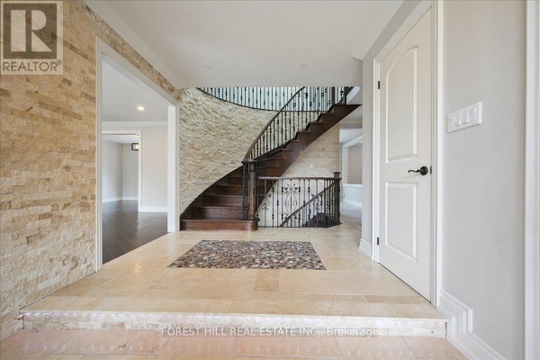 Spacious foyer with curved staircase and stone accent wall - 2579 Kenna Court, Mississauga