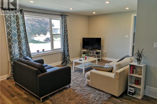 Living room with a large window, two sofas, a coffee table, and a TV. - 258 Carson Drive Unit# Main, Hamilton