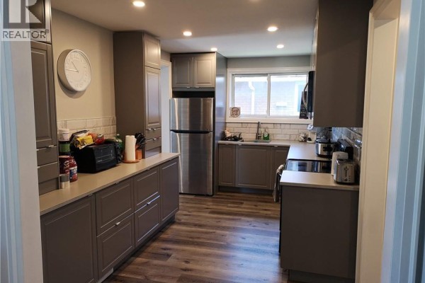 Kitchen with grey cabinets, stainless steel appliances, a double sink, and a window. - 258 Carson Drive Unit# Main, Hamilton