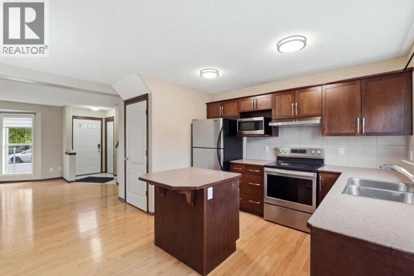 Living room with hardwood floors, a large bay window, and an arched entryway. - 258 Cranberry Place Se, Calgary