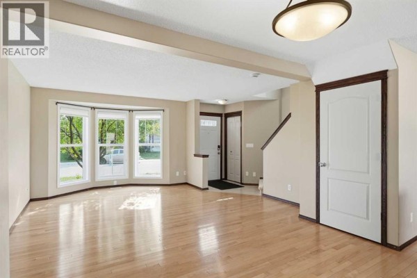 Kitchen with dark wood cabinets, stainless steel appliances, light countertops, and a large window. - 258 Cranberry Place Se, Calgary
