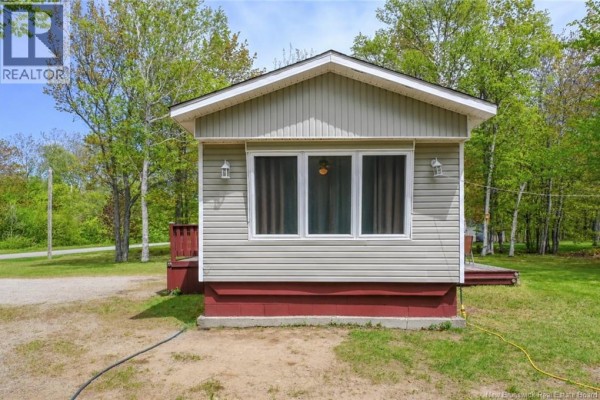 A kitchen with brown cabinets, white appliances, a window overlooking trees, and a rustic wooden kitchen island. - 258 Du Bocage Street, Saint Leolin
