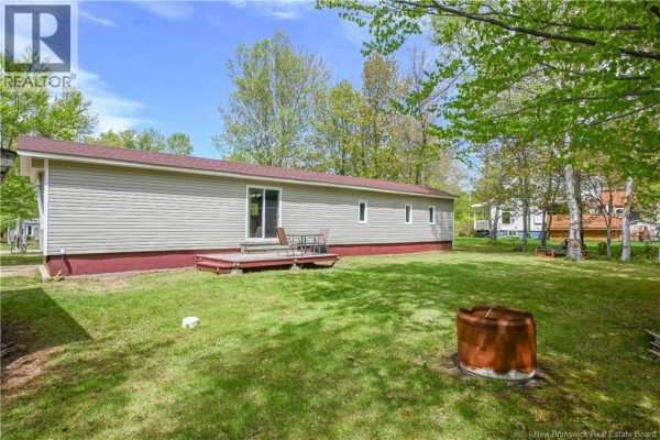 A kitchen with a sliding glass door opening to a yard, a kitchen island, and a doorway leading to a living room. - 258 Du Bocage Street, Saint Leolin