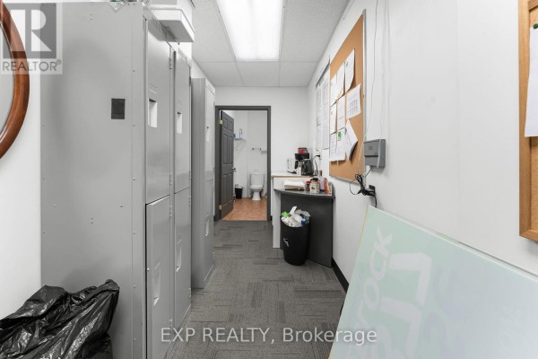 Storage lockers and a bulletin board in a hallway leading to a restroom. - 258 Lakeshore Road E, Mississauga