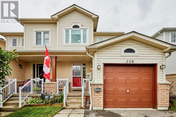 Front view of a beige townhouse with tan siding, brick accents, and a brown garage door. - 258 Swindells Street, Clarington