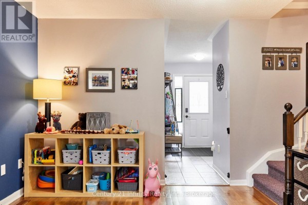 Interior hallway with light wood floors, a storage cube with children's toys, and a staircase. - 258 Swindells Street, Clarington