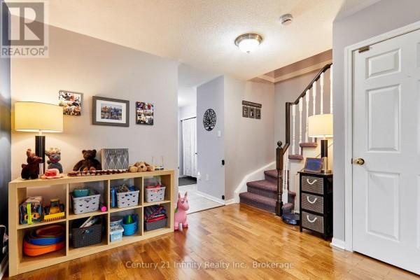 Hallway entrance with light wood floors, a staircase with a dark carpet runner, and a white door. - 258 Swindells Street, Clarington