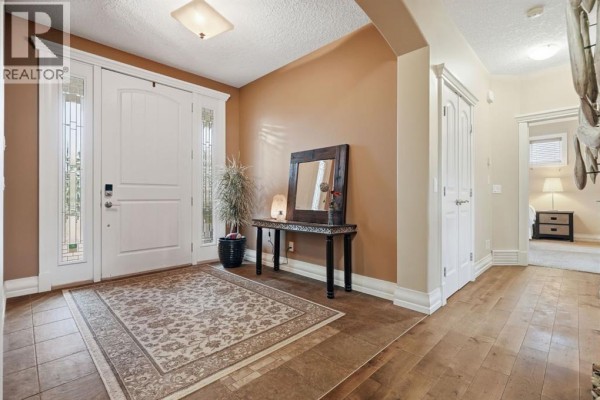 Interior view of a home entryway with tiled flooring, a patterned rug, and a console table. - 258244 10 Street E, Rural Foothills County