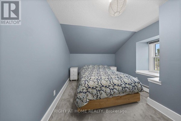 A bedroom with blue walls, a wooden bed frame, and a sloped ceiling. - 2584 Highway 43 Highway, Montague