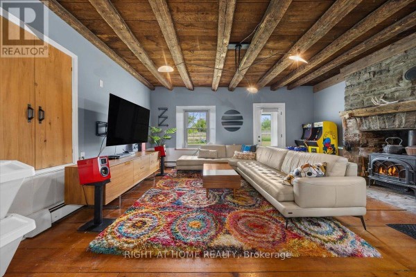 A cozy living room with a sectional sofa, fireplace, wood-beamed ceiling, and entertainment center. - 2584 Highway 43 Highway, Montague