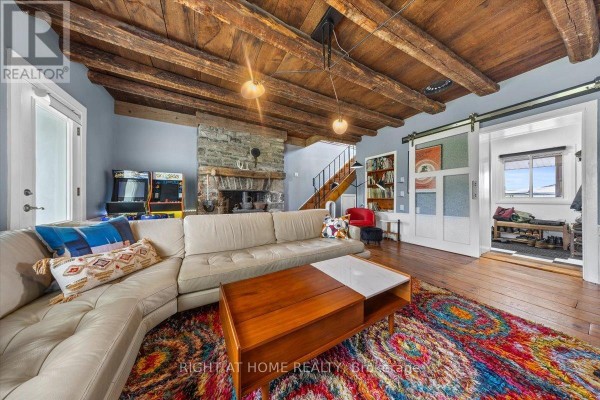 Spacious living room with sectional sofa, stone fireplace, wood-beamed ceiling, and sliding barn door. - 2584 Highway 43 Highway, Montague