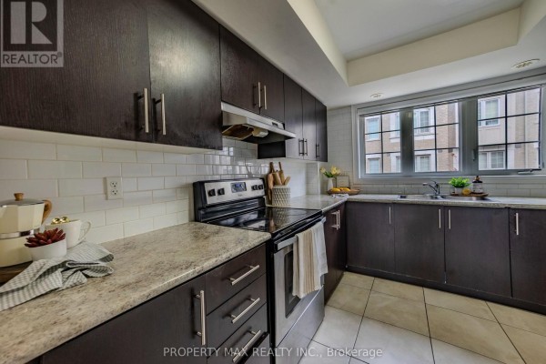 Kitchen with dark cabinetry, stainless steel appliances, and large windows - 2589 Bromus Path, Oshawa