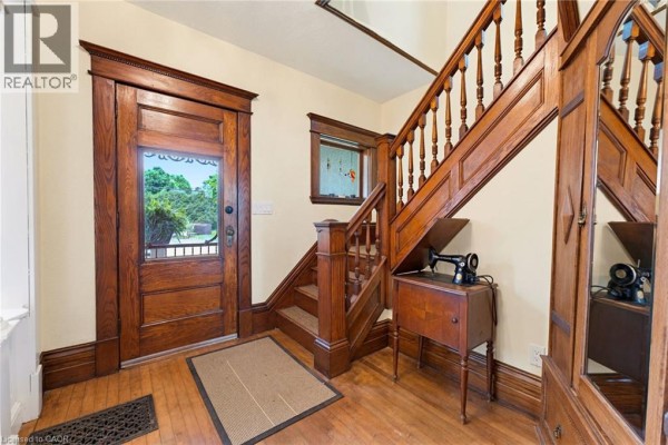 Entryway with a glass-paneled wooden door, wooden staircase, and hardwood floors. - 2589 W Jerseyville Road W, Jerseyville