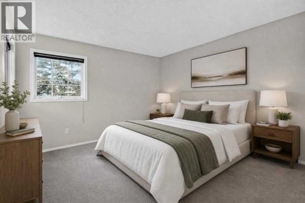 A bedroom with a queen-size bed, neutral bedding, and wooden nightstands. - 259 Coachway Road Sw, Calgary