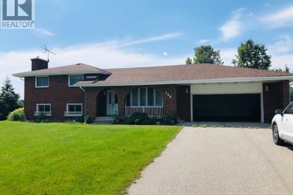 A two-story brick house with a covered entrance, arched windows, and a two-car garage, set on a green lawn. - 259 County Rd 46, Lakeshore