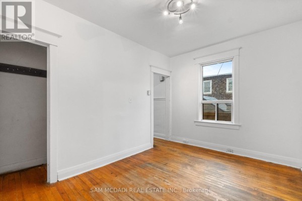 Empty room with hardwood floors, white walls, and a window for natural light. - 259 Milverton Boulevard, Toronto