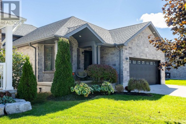 View of the stone house entrance with a dark grey garage door and arch window. - 2591 7th Avenue E, Owen Sound