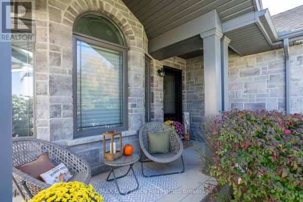 Street view of a stone and blue siding house with a paved driveway and lawn. - 2591 7th Avenue E, Owen Sound