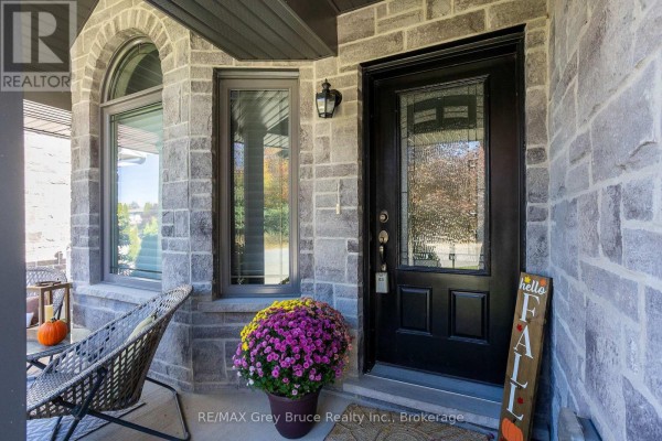 Close-up of the front door with a glass inset, flanked by stone and a window. - 2591 7th Avenue E, Owen Sound