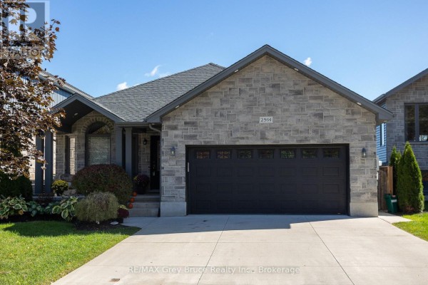 Living room with hardwood floors, two sofas, an oval coffee table, and double doors. - 2591 7th Avenue E, Owen Sound