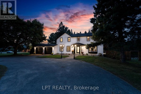 White house with black trim and a three-car garage at dusk with a colorful sky. - 2598 Highway 34 Road, Hawkesbury