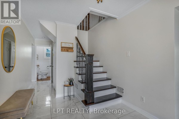 Interior hallway with a bench, mirror, and staircase featuring dark wood railings and white risers. - 2598 Highway 34 Road, Hawkesbury