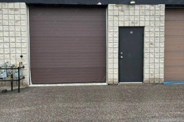Rear exterior with a brown garage door, a black service door, and concrete gravel. - 26 - 4 Vata Court, Aurora