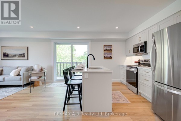 Open concept living and kitchen area with island, sofa, and balcony access. - 26 - 428 Queen Street W, St  Marys