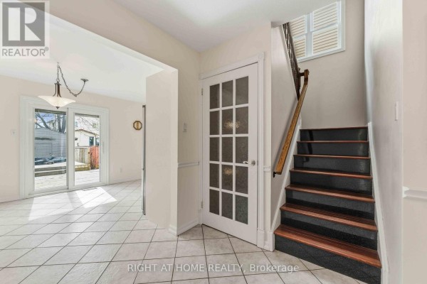 View from the entryway looking towards a dining area with sliding glass doors opening to a backyard deck. - 26 Denham Way, Ottawa