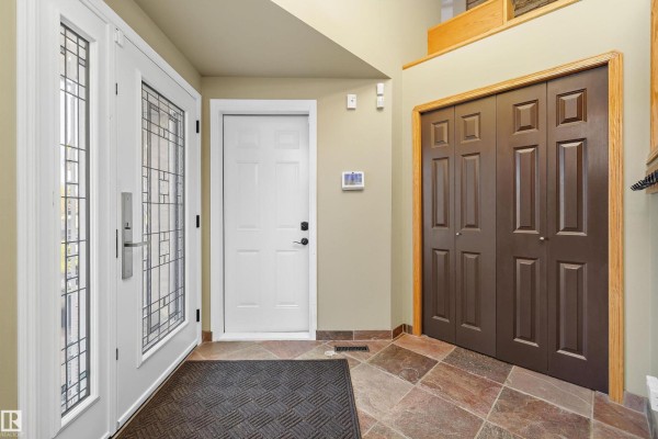 Interior entryway with slate tile flooring, a white door, and a dark brown double closet. - 26 Fairway Dr, Spruce Grove