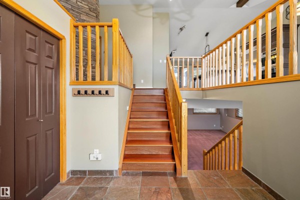 Interior view of a wooden staircase with light tan walls and slate tile flooring. - 26 Fairway Dr, Spruce Grove