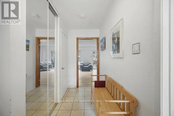 Interior hallway with tiled floor, mirrored closet doors, and access to rooms. - 26 Fanshawe Drive, Brampton