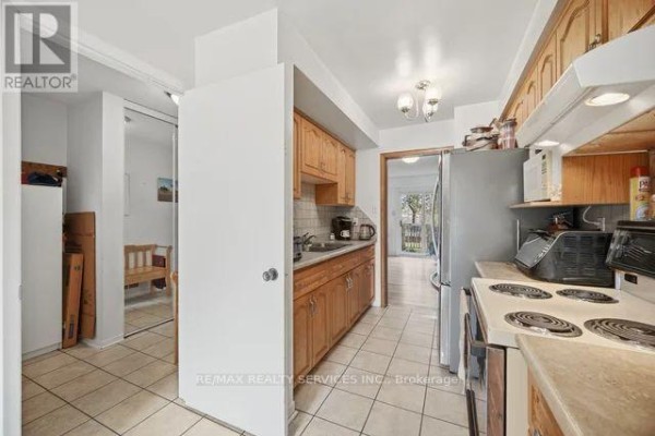 Kitchen with light wood cabinets, stainless steel appliances, and tiled flooring. - 26 Fanshawe Drive, Brampton