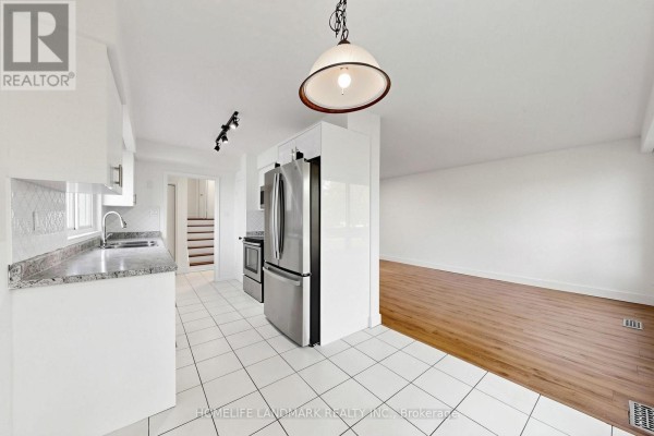 Kitchen with white tile floor and backsplash, stainless steel appliances, and granite countertops. - 26 Fenside Drive, Toronto