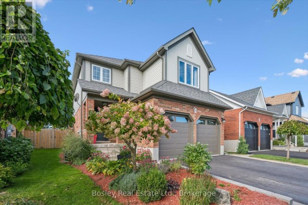 Side exterior view of a house featuring brick and vinyl siding, a front porch, and landscaping. - 26 Glengarry Road, Orangeville