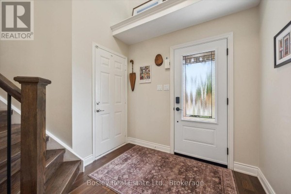 Interior entryway with a white front door, a rug, and a wooden staircase. - 26 Glengarry Road, Orangeville