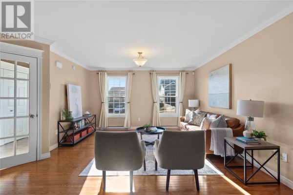 Living room with hardwood floors, a brown leather sofa, two grey chairs, and large windows. - 26 Hamlet Street, St  John S