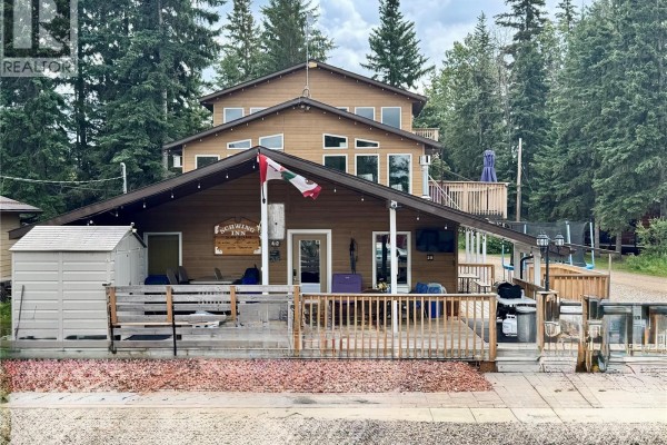 Front exterior view of a wooden house with a covered porch, decks, and an attached shed with outdoor seating. - 28 Mathews Crescent, Turtle View