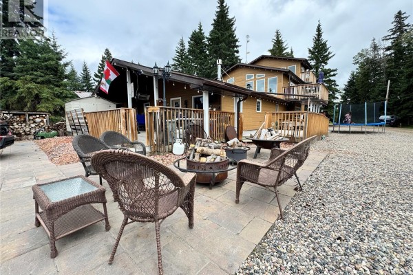 Outdoor seating area with wicker chairs and a fire pit on a stone patio, with a wooden house in the background. - 28 Mathews Crescent, Turtle View