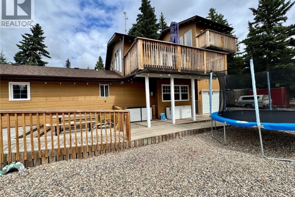 Close-up view of the house's wooden decks, outdoor storage units, and a trampoline in the gravel yard. - 28 Mathews Crescent, Turtle View
