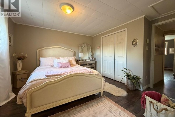 Bedroom with a bed, dresser, closet doors, and a view into an adjacent room. - 26 Octave Breau, Neguac