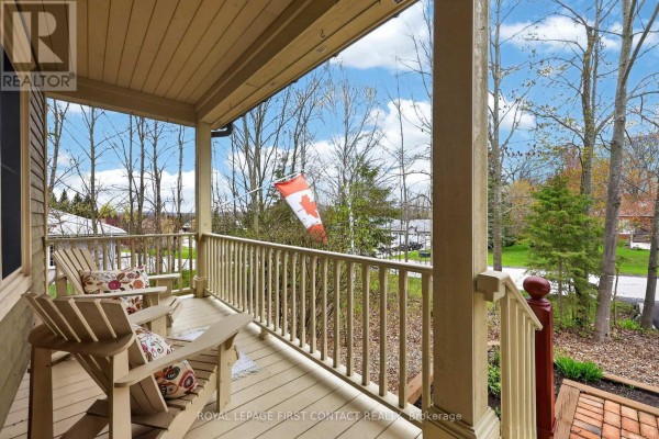 Covered front porch with two Adirondack chairs and a view of trees and distant houses. - 26 Paddy Dunn's Circle, Springwater