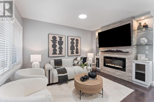 Living room with a sectional sofa, modern fireplace, mounted television, and beige rug. - 26 Roxaline Street, Toronto