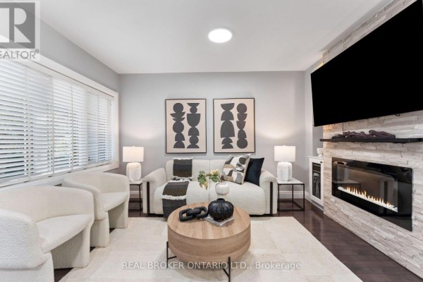 Living room featuring a white sectional sofa, fireplace with stone surround, and wood coffee table. - 26 Roxaline Street, Toronto