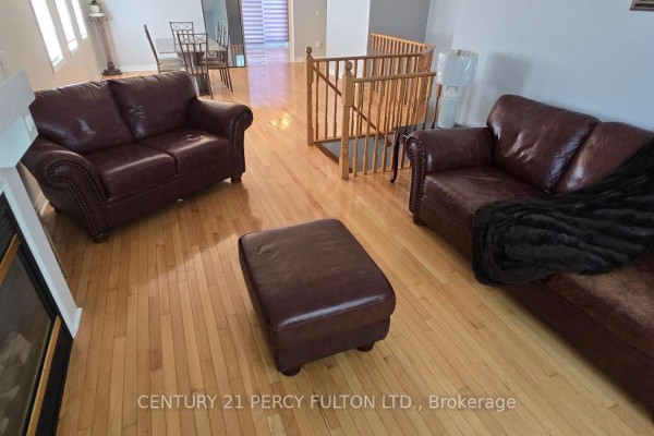 Living room area with two brown leather sofas, an ottoman, and a fireplace. - 26 Rushbrook Drive, Brampton