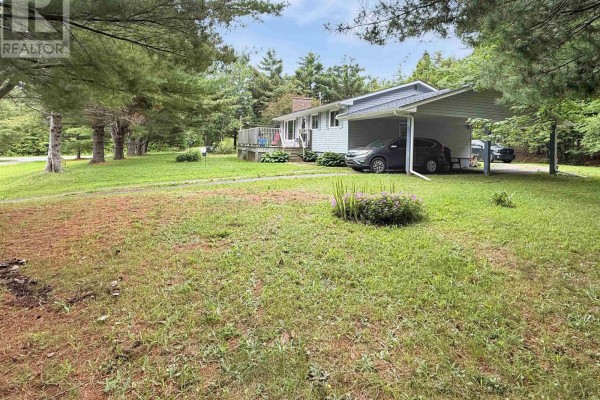 View of the house from the driveway, surrounded by green grass and mature trees. - 26 South Hill Drive, Abercrombie