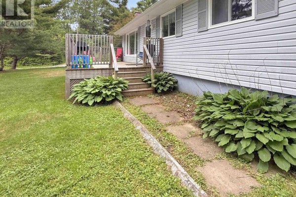 Front entrance with a wooden deck, stairs, and large hosta plants flanking the walkway. - 26 South Hill Drive, Abercrombie